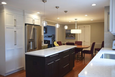 Large transitional galley medium tone wood floor and brown floor eat-in kitchen photo in New York with an undermount sink, shaker cabinets, white cabinets, marble countertops, stainless steel appliances and an island