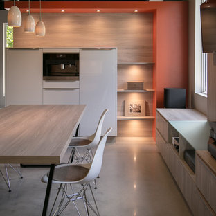 Foto di una cucina moderna di medie dimensioni con lavello sottopiano, ante lisce, ante gialle, top in quarzo composito, paraspruzzi arancione, paraspruzzi in lastra di pietra, elettrodomestici in acciaio inossidabile, pavimento in cemento e penisola