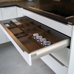 Idée de décoration pour une cuisine ouverte minimaliste en L de taille moyenne avec un évier encastré, un placard à porte plane, des portes de placard jaunes, un plan de travail en quartz modifié, une crédence orange, une crédence en dalle de pierre, un électroménager en acier inoxydable, béton au sol et une péninsule.