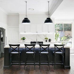 Inspiration for a large transitional l-shaped open plan kitchen in Sydney with shaker cabinets, black cabinets, tile benchtops, multi-coloured splashback, ceramic splashback, medium hardwood floors, with island, brown floor, a single-bowl sink, black appliances and white benchtop.