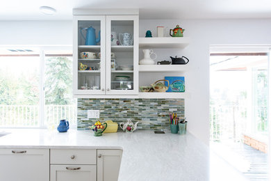 Example of a mid-sized trendy u-shaped eat-in kitchen design in Seattle with shaker cabinets, white cabinets, quartzite countertops, green backsplash, glass tile backsplash, an island and white countertops