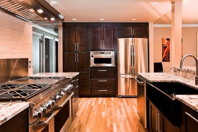 Inspiration for a mid-sized contemporary u-shaped light wood floor enclosed kitchen remodel in Seattle with a farmhouse sink, flat-panel cabinets, dark wood cabinets, granite countertops, beige backsplash, porcelain backsplash, stainless steel appliances and no island