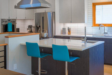 Mid-sized trendy u-shaped light wood floor and beige floor eat-in kitchen photo in Seattle with an undermount sink, flat-panel cabinets, gray cabinets, quartz countertops, white backsplash, subway tile backsplash, stainless steel appliances, an island and white countertops