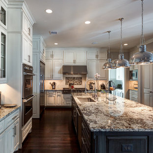 Inspiration for a large transitional l-shaped dark wood floor eat-in kitchen remodel in Houston with granite countertops, an undermount sink, raised-panel cabinets, white cabinets, white backsplash, ceramic backsplash, stainless steel appliances and an island