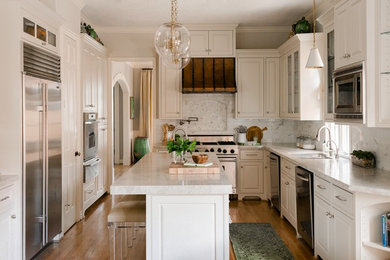 Geschlossene Klassische Küche in L-Form mit Doppelwaschbecken, profilierten Schrankfronten, weißen Schränken, Küchenrückwand in Grau, Küchengeräten aus Edelstahl, braunem Holzboden, Kücheninsel und grauer Arbeitsplatte in Houston