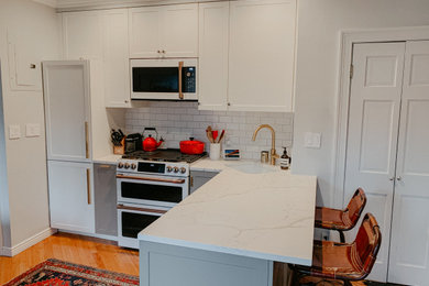Small trendy l-shaped light wood floor kitchen photo in New York with an undermount sink, shaker cabinets, white cabinets, white backsplash, subway tile backsplash, stainless steel appliances, a peninsula and white countertops