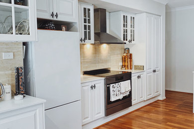 Modelo de cocina lineal contemporánea de tamaño medio abierta con armarios estilo shaker, puertas de armario blancas, encimera de acrílico, salpicadero beige, una isla y encimeras blancas