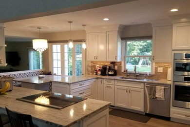 Inspiration for a mid-sized transitional u-shaped medium tone wood floor and brown floor eat-in kitchen remodel in Philadelphia with an undermount sink, recessed-panel cabinets, white cabinets, granite countertops, gray backsplash, glass tile backsplash, stainless steel appliances and a peninsula