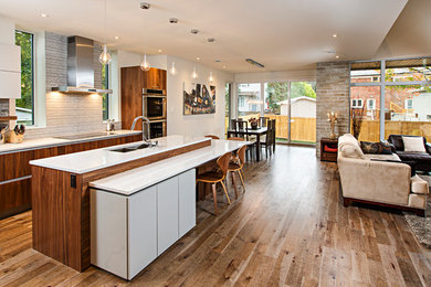 Example of a large trendy l-shaped medium tone wood floor eat-in kitchen design in Ottawa with an undermount sink, glass-front cabinets, medium tone wood cabinets, quartzite countertops, beige backsplash, glass tile backsplash, stainless steel appliances and an island