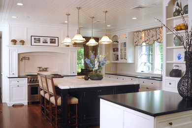 Example of a large classic l-shaped dark wood floor enclosed kitchen design in New York with an undermount sink, shaker cabinets, white cabinets, marble countertops, white backsplash, subway tile backsplash, stainless steel appliances and an island