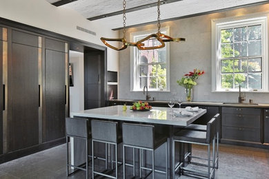 Large minimalist l-shaped limestone floor and gray floor enclosed kitchen photo in New York with an integrated sink, flat-panel cabinets, dark wood cabinets, gray backsplash, stone tile backsplash, paneled appliances, an island and solid surface countertops