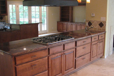 Imagen de cocina tradicional grande con armarios con paneles con relieve, puertas de armario de madera en tonos medios, encimera de granito y salpicadero de metal