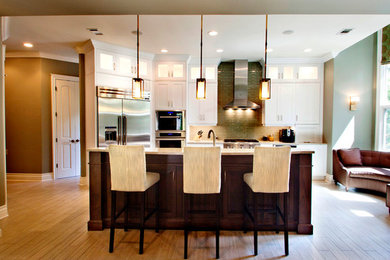 Inspiration for a large transitional l-shaped light wood floor kitchen remodel in Austin with white cabinets, granite countertops, green backsplash, ceramic backsplash, stainless steel appliances, an island and shaker cabinets