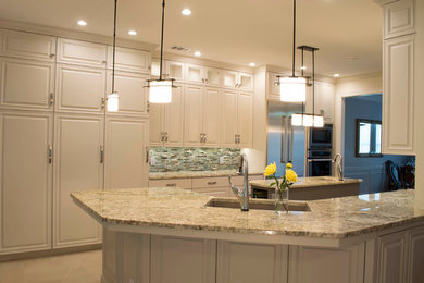 Large transitional porcelain tile kitchen photo in Austin with a double-bowl sink, raised-panel cabinets, gray cabinets, granite countertops, green backsplash, glass tile backsplash, stainless steel appliances and an island