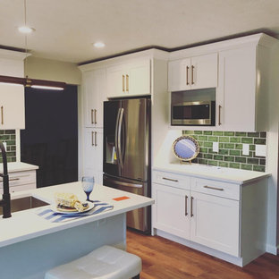 This is an example of a mid-sized midcentury u-shaped separate kitchen in Cleveland with an undermount sink, shaker cabinets, white cabinets, quartz benchtops, green splashback, subway tile splashback, stainless steel appliances, vinyl floors, a peninsula, brown floor and white benchtop.