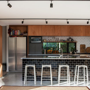 Ispirazione per una cucina minimal con lavello a doppia vasca, paraspruzzi bianco, paraspruzzi con piastrelle diamantate, elettrodomestici in acciaio inossidabile e pavimento in cemento
