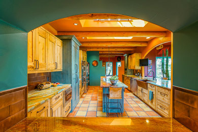 Bild på ett stort amerikanskt kök, med en rustik diskho, släta luckor, skåp i ljust trä, granitbänkskiva, stänkskydd med metallisk yta, stänkskydd i metallkakel, rostfria vitvaror, klinkergolv i terrakotta och en köksö