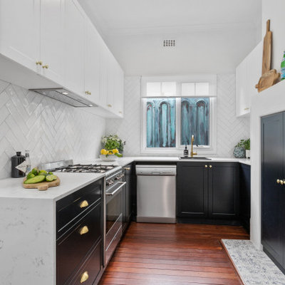 Inspiration for a transitional u-shaped dark wood floor and brown floor kitchen remodel in Perth with a drop-in sink, shaker cabinets, black cabinets, white backsplash, stainless steel appliances and white countertops