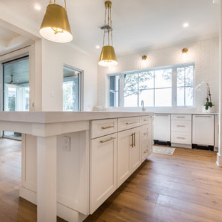 Immagine di una grande cucina country con lavello stile country, ante in stile shaker, ante bianche, top in quarzo composito, paraspruzzi bianco, paraspruzzi in mattoni, elettrodomestici da incasso, pavimento in legno massello medio, pavimento marrone e top giallo