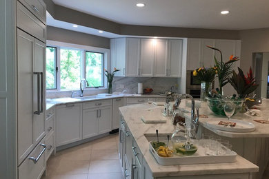 Inspiration for a mid-sized transitional l-shaped ceramic tile and beige floor open concept kitchen remodel in Boston with an undermount sink, recessed-panel cabinets, white cabinets, marble countertops, white backsplash, stone slab backsplash, stainless steel appliances and an island
