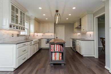 Example of a mid-sized country u-shaped medium tone wood floor and brown floor eat-in kitchen design in Other with a farmhouse sink, raised-panel cabinets, white cabinets, quartz countertops, multicolored backsplash, marble backsplash, stainless steel appliances and an island