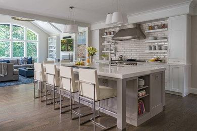 Design ideas for a traditional kitchen in Boston with shaker cabinets, white cabinets, engineered stone countertops, white splashback, metro tiled splashback, stainless steel appliances, light hardwood flooring, multiple islands and beige floors.