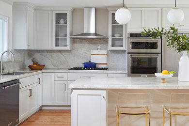 Inspiration for a mid-sized transitional l-shaped medium tone wood floor and brown floor open concept kitchen remodel in San Francisco with a single-bowl sink, shaker cabinets, gray cabinets, quartzite countertops, gray backsplash, stone slab backsplash, stainless steel appliances, an island and gray countertops