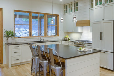Eat-in kitchen - country l-shaped light wood floor eat-in kitchen idea in Other with an undermount sink, shaker cabinets, white cabinets, granite countertops, white backsplash, ceramic backsplash, paneled appliances and an island