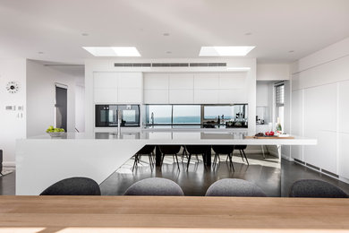 Идея дизайна: большая кухня-гостиная в стиле модернизм с столешницей из акрилового камня, зеркальным фартуком, бетонным полом и серым полом