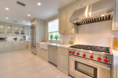 Example of a large transitional l-shaped white floor kitchen design in Los Angeles with a farmhouse sink, shaker cabinets, gray cabinets, marble countertops, white backsplash, subway tile backsplash and stainless steel appliances