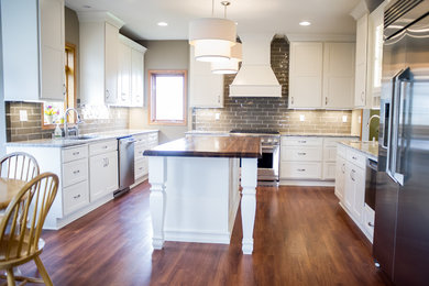 Large transitional galley medium tone wood floor open concept kitchen photo in Other with recessed-panel cabinets, white cabinets, wood countertops, beige backsplash, ceramic backsplash, stainless steel appliances, two islands and an undermount sink