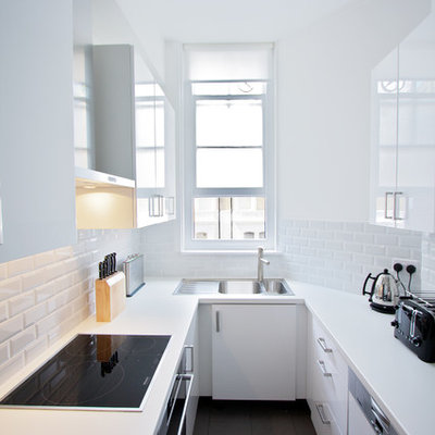 Enclosed kitchen - mid-sized contemporary u-shaped ceramic tile enclosed kitchen idea in London with a double-bowl sink, flat-panel cabinets, laminate countertops, white backsplash, ceramic backsplash, no island and paneled appliances