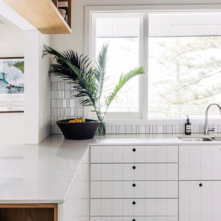 Design ideas for a contemporary l-shaped kitchen in Sydney with a double-bowl sink, white cabinets, white splashback, mosaic tile splashback, a peninsula, black floor, white benchtop and painted wood floors.
