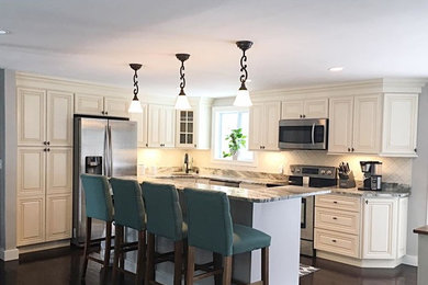 Mid-sized elegant l-shaped brown floor and dark wood floor open concept kitchen photo in Boston with an undermount sink, raised-panel cabinets, beige cabinets, granite countertops, beige backsplash, porcelain backsplash, stainless steel appliances, an island and multicolored countertops