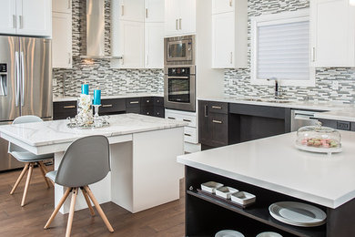 Large trendy u-shaped medium tone wood floor and brown floor eat-in kitchen photo in Calgary with an undermount sink, shaker cabinets, white cabinets, wood countertops, gray backsplash, glass tile backsplash, stainless steel appliances and an island