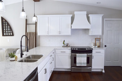 Foto på ett lantligt kök, med en undermonterad diskho, vita skåp, bänkskiva i kvarts, vitt stänkskydd, stänkskydd i tunnelbanekakel, rostfria vitvaror, mörkt trägolv och brunt golv