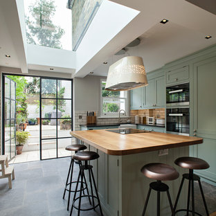 Ispirazione per una cucina a L minimal di medie dimensioni con lavello stile country, ante in stile shaker, ante verdi, top in legno, paraspruzzi bianco, paraspruzzi con piastrelle diamantate, elettrodomestici neri, pavimento con piastrelle in ceramica e isola