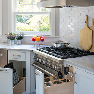 Mid-sized transitional eat-in kitchen designs - Inspiration for a mid-sized transitional l-shaped dark wood floor eat-in kitchen remodel in New York with an undermount sink, shaker cabinets, white cabinets, quartzite countertops, white backsplash, ceramic backsplash, stainless steel appliances and an island