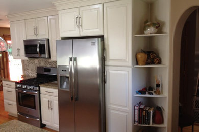 Eat-in kitchen - mid-sized traditional galley dark wood floor and brown floor eat-in kitchen idea in New York with raised-panel cabinets, white cabinets, granite countertops, multicolored backsplash, mosaic tile backsplash, stainless steel appliances, an island and a double-bowl sink