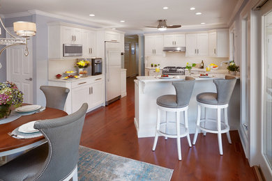 Example of a mid-sized transitional u-shaped medium tone wood floor and brown floor eat-in kitchen design in Other with an undermount sink, recessed-panel cabinets, white cabinets, quartz countertops, white backsplash, stone slab backsplash, stainless steel appliances, a peninsula and white countertops