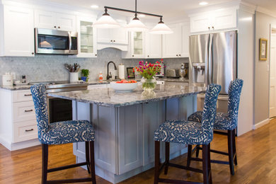 Eat-in kitchen - small coastal l-shaped medium tone wood floor and brown floor eat-in kitchen idea in Boston with an undermount sink, shaker cabinets, white cabinets, quartz countertops, marble backsplash, stainless steel appliances and an island