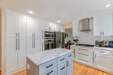 Example of a mid-sized minimalist u-shaped medium tone wood floor eat-in kitchen design in Seattle with an undermount sink, shaker cabinets, white cabinets, quartzite countertops, white backsplash, ceramic backsplash, stainless steel appliances, an island and white countertops