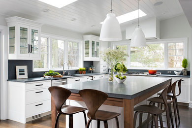 Eat-in kitchen - large transitional l-shaped medium tone wood floor eat-in kitchen idea in New York with a single-bowl sink, shaker cabinets, white cabinets, limestone countertops, gray backsplash, stone slab backsplash, stainless steel appliances and an island