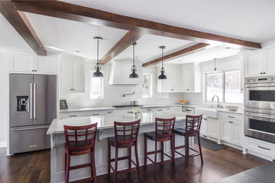 Eat-in kitchen - large transitional l-shaped dark wood floor and brown floor eat-in kitchen idea in Minneapolis with a farmhouse sink, recessed-panel cabinets, white cabinets, quartzite countertops, white backsplash, subway tile backsplash, stainless steel appliances, an island and multicolored countertops