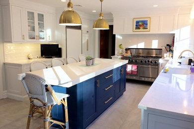 Example of a mid-sized transitional l-shaped porcelain tile and gray floor eat-in kitchen design in New York with a farmhouse sink, shaker cabinets, white cabinets, quartz countertops, white backsplash, subway tile backsplash, stainless steel appliances and an island