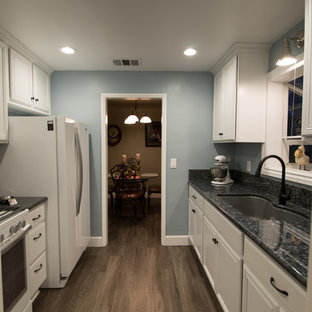 Small transitional enclosed kitchen designs - Small transitional galley vinyl floor enclosed kitchen photo in Other with an undermount sink, flat-panel cabinets, white cabinets, granite countertops and white appliances