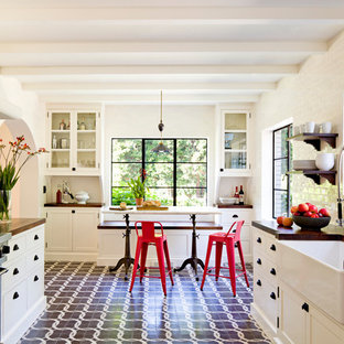 Mediterranean enclosed kitchen photos - Inspiration for a mediterranean galley enclosed kitchen remodel in Portland with a farmhouse sink, shaker cabinets, white cabinets, wood countertops, white backsplash, subway tile backsplash and stainless steel appliances