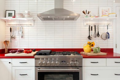 ブリッジポートにある北欧スタイルのおしゃれなキッチン (アンダーカウンターシンク、シェーカースタイル扉のキャビネット、白いキャビネット、クオーツストーンカウンター、白いキッチンパネル、セラミックタイルのキッチンパネル、シルバーの調理設備、磁器タイルの床、赤いキッチンカウンター) の写真