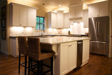 Eat-in kitchen - mid-sized transitional l-shaped dark wood floor and brown floor eat-in kitchen idea in Birmingham with a farmhouse sink, shaker cabinets, white cabinets, marble countertops, gray backsplash, marble backsplash, stainless steel appliances and an island