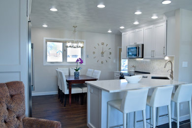 Example of a trendy eat-in kitchen design in Other with shaker cabinets, white cabinets, marble countertops, white backsplash, stainless steel appliances, an island and white countertops